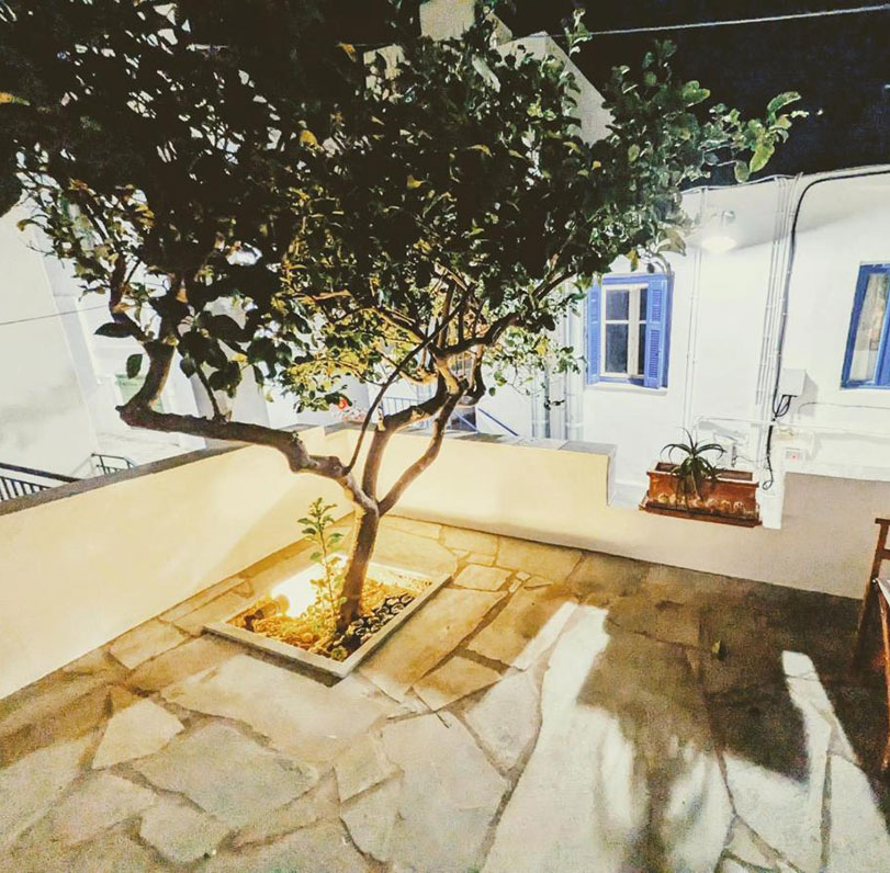 Πλακόστρωτη αυλή με δέντρα στα δωμάτια το Στενό στη Σίφνο